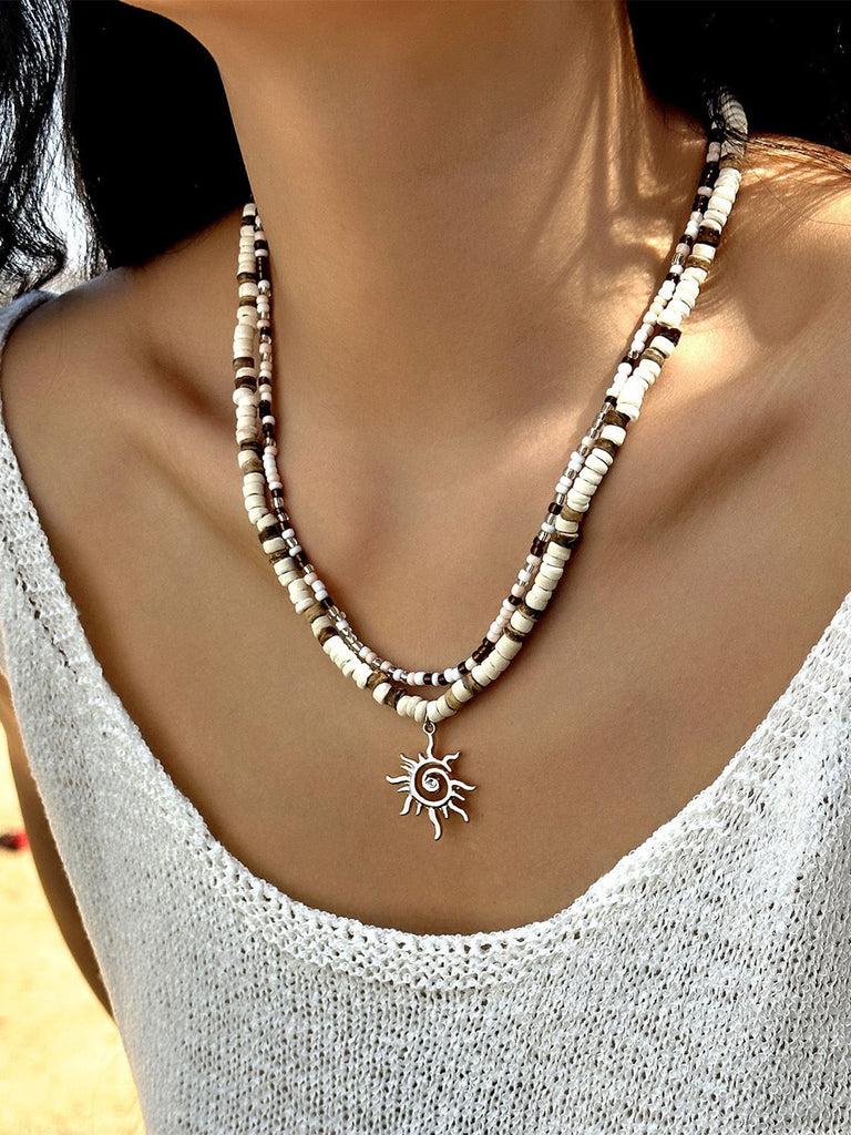 Collier plusieurs rangs pendentif soleil perles blanches et brunes