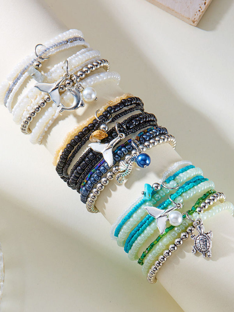Set of three beaded bracelets with charms on a light background