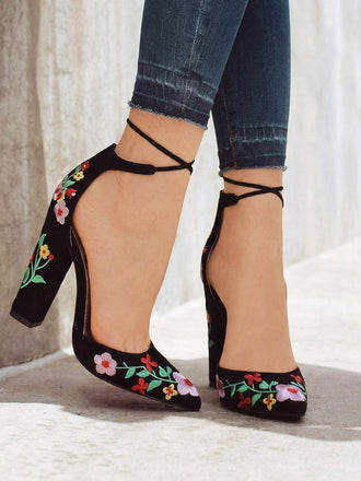 Chaussures noires à talons hauts ornées de broderies florales, portées avec un jean retroussé.