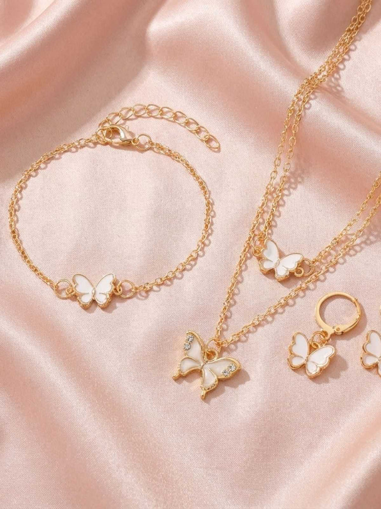 Ensemble de bijoux en or avec des breloques papillon roses sur un fond en tissu rose
