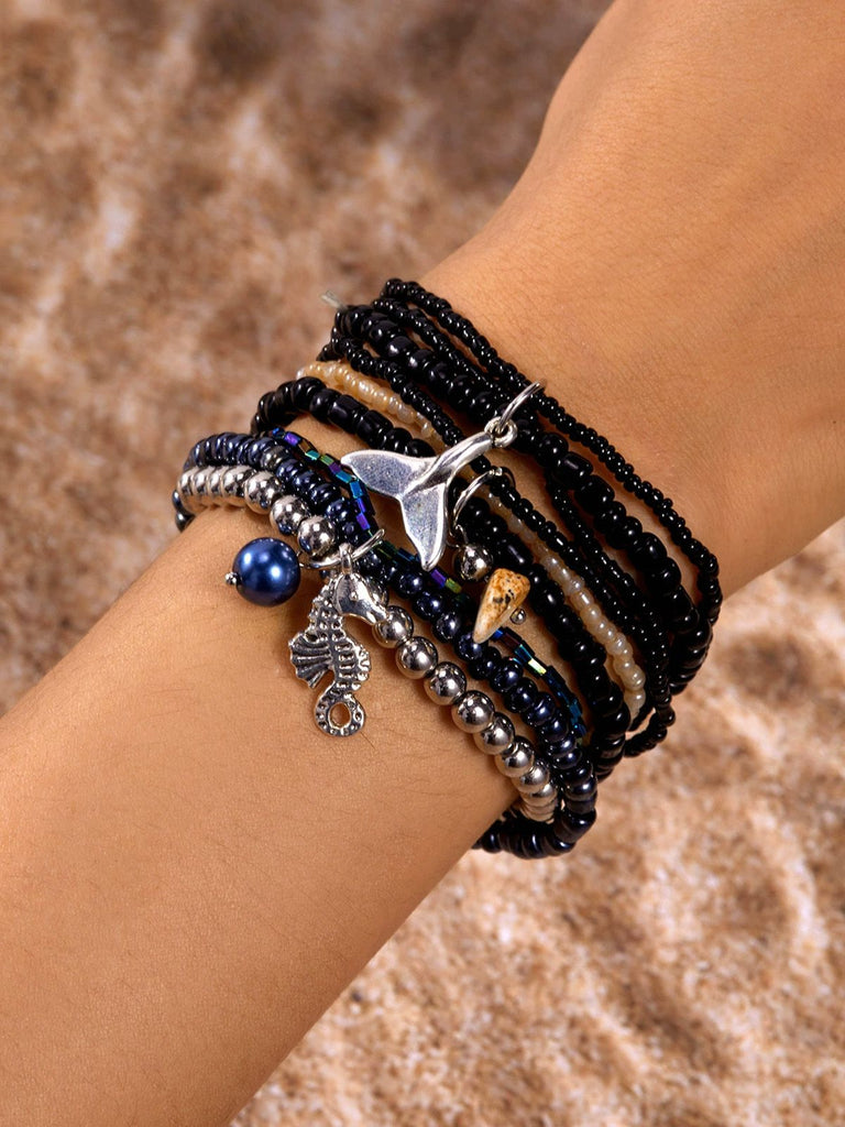 Plusieurs bracelets à breloques sur un poignet, sur fond marron