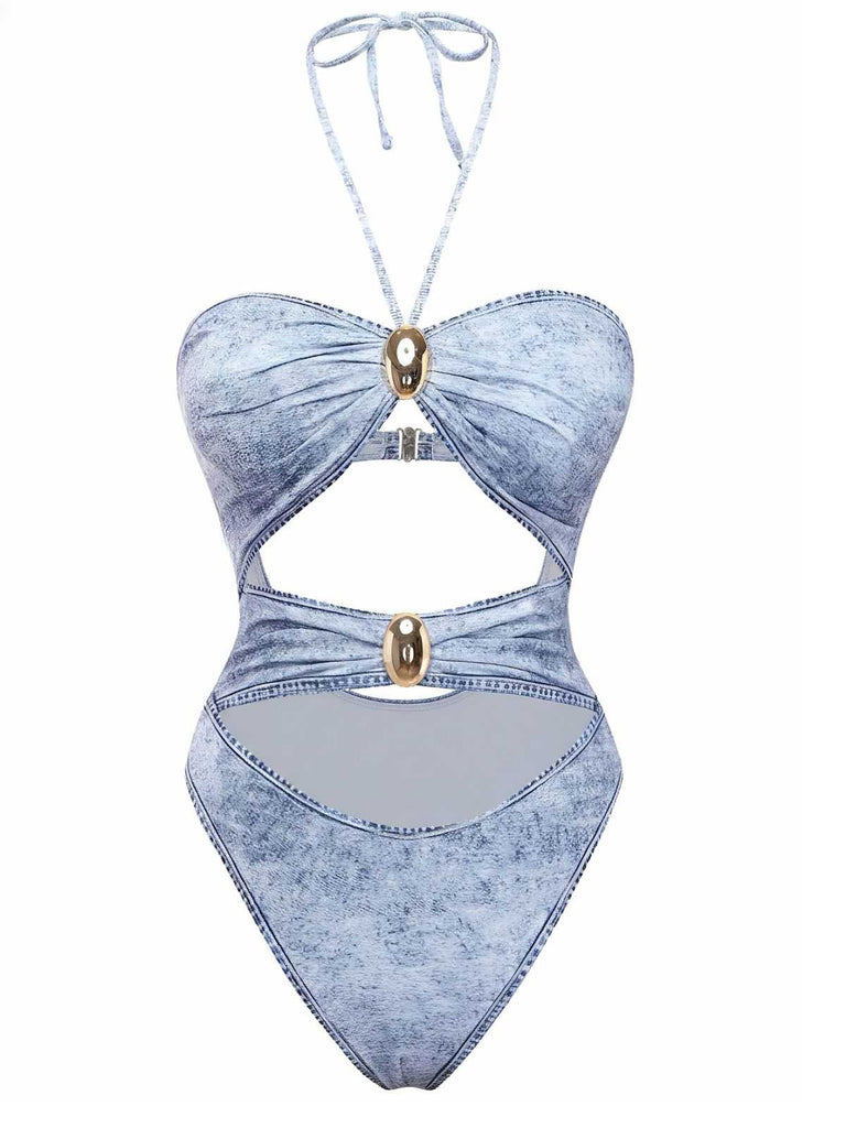 Un maillot de bain une pièce bleu clair imprimé denim, doté d'un col halter, de multiples découpes sur le devant et d'ornements métalliques dorés.