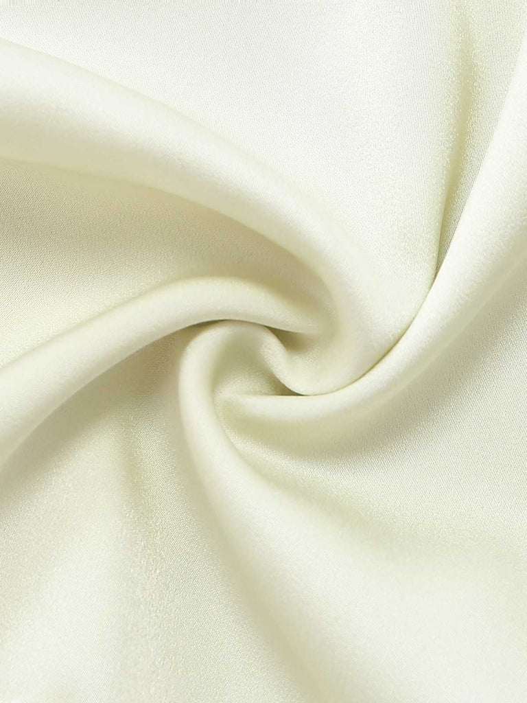 Macro shot of the soft, draped cream satin fabric used for the pajama shorts.