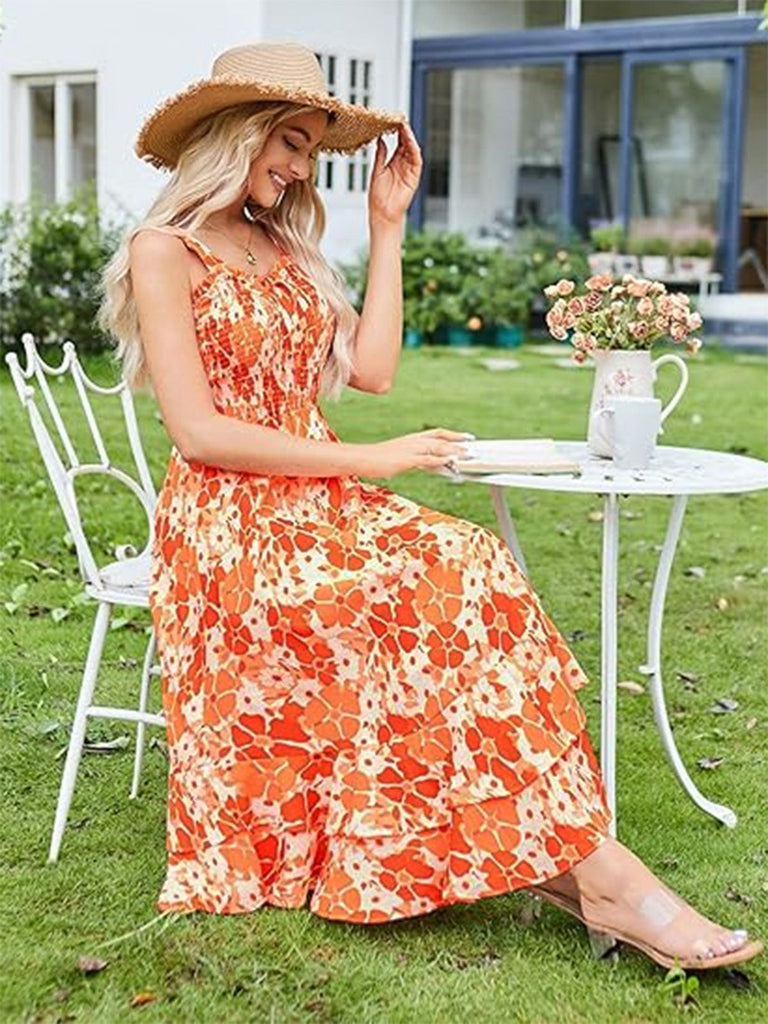 Woman in an orange floral dress sitting outdoors on a sunny day.