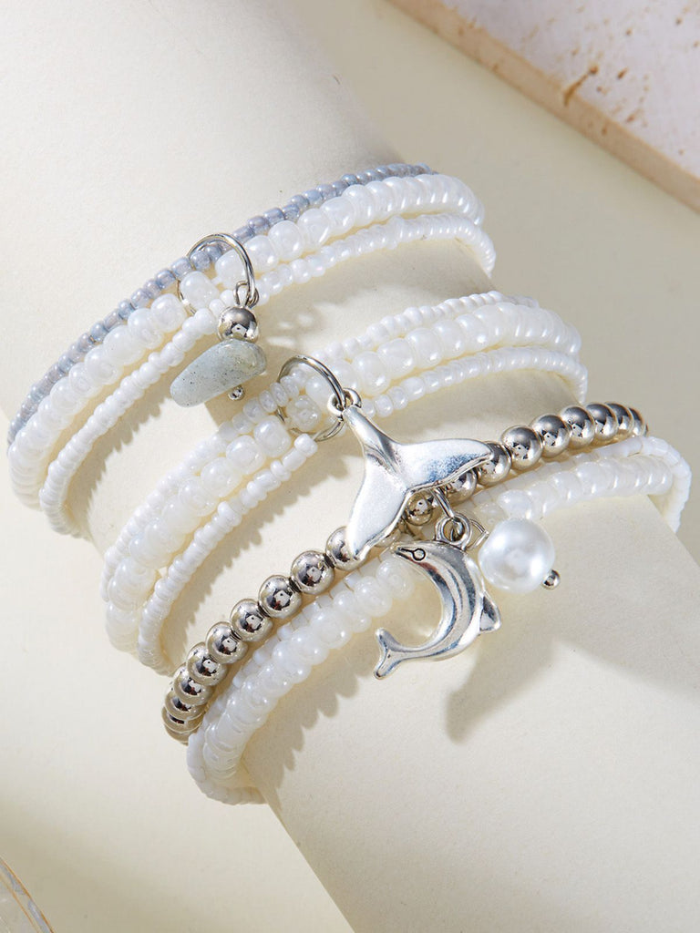 Set of pearl and silver beaded bracelets with charms on a white surface